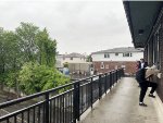 People wait underneath the roof on the pedestrian bridge as a way to stay dry at Kingsland Station